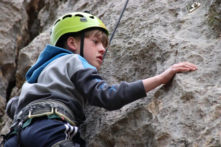 Niño escalando una pared de roca natural